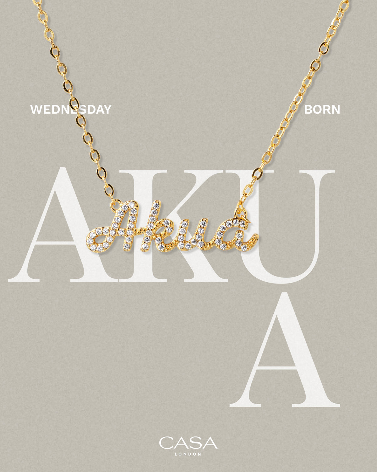 A product shot of CASA London’s 18k gold Akua Pavé Necklace. The delicate gold chain features a script pendant spelling "Akua," encrusted with shimmering pavé-set stones against a neutral, textured background. Overlaid text reads "WEDNESDAY BORN," highlighting the brand's commitment to celebrating cultural heritage and personal narratives through modern luxury.
