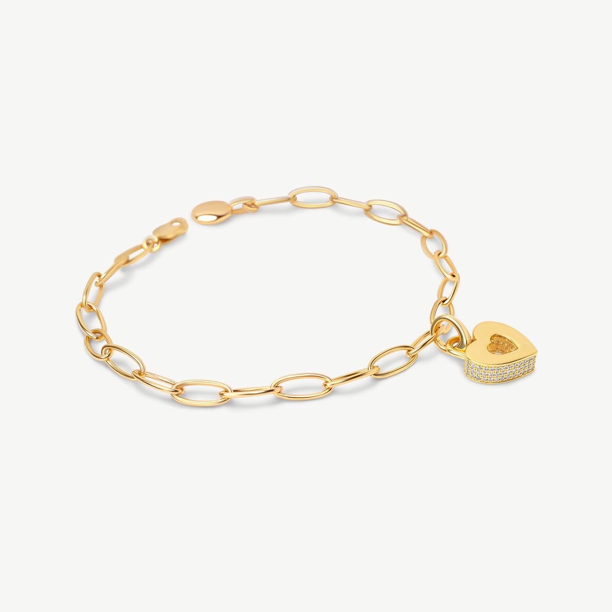 CASA LONDON Akoma Pavé Charm in 18ct gold vermeil styled on the Royal Insignia oval link chain bracelet. Heart-shaped Adinkra charm with white zirconia pavé stones, shown on a cream background.