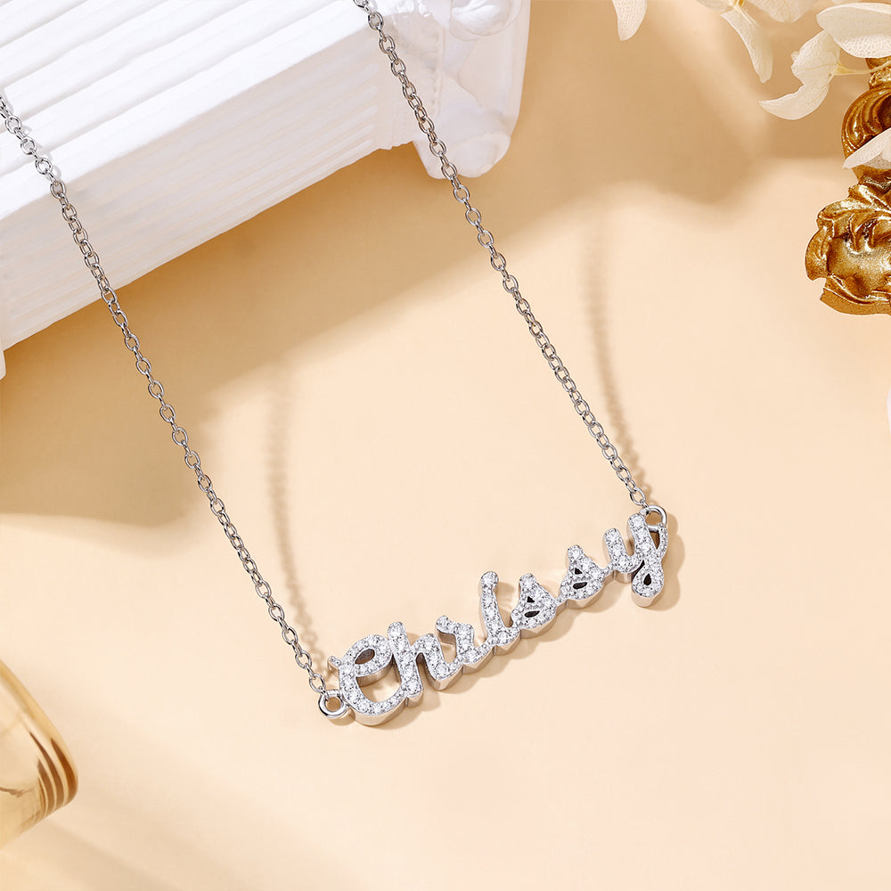 CASA London Custom Pavé Name Necklace in rhodium silver on S925 sterling silver, featuring hand-set moissanite stones on a cable chain. Product flat lay.
