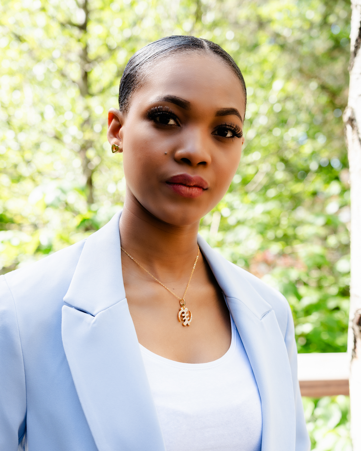 CASA LONDON Gye Nyame Pendant in 18ct gold plated, worn by a model. Symbolizing the 'Supremacy of God', this pendant also adds cultural significance to your look, versatile and timeless, pair it with a chain or bracelet for a complete look.