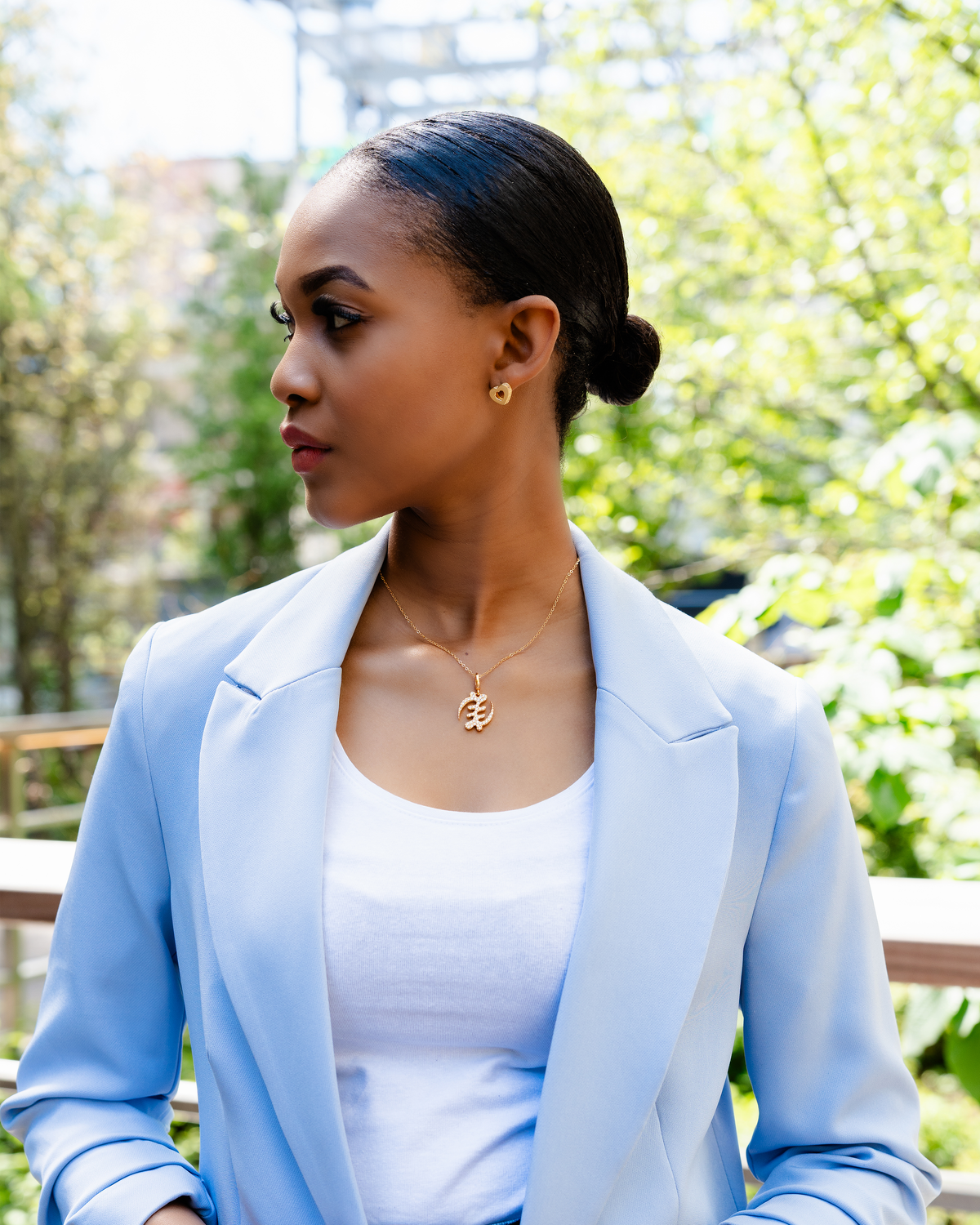 CASA LONDON Gye Nyame Pendant in 18ct gold plated, worn by a model. Symbolizing the 'Supremacy of God', this pendant also adds cultural significance to your look, versatile and timeless, pair it with a chain or bracelet for a complete look.