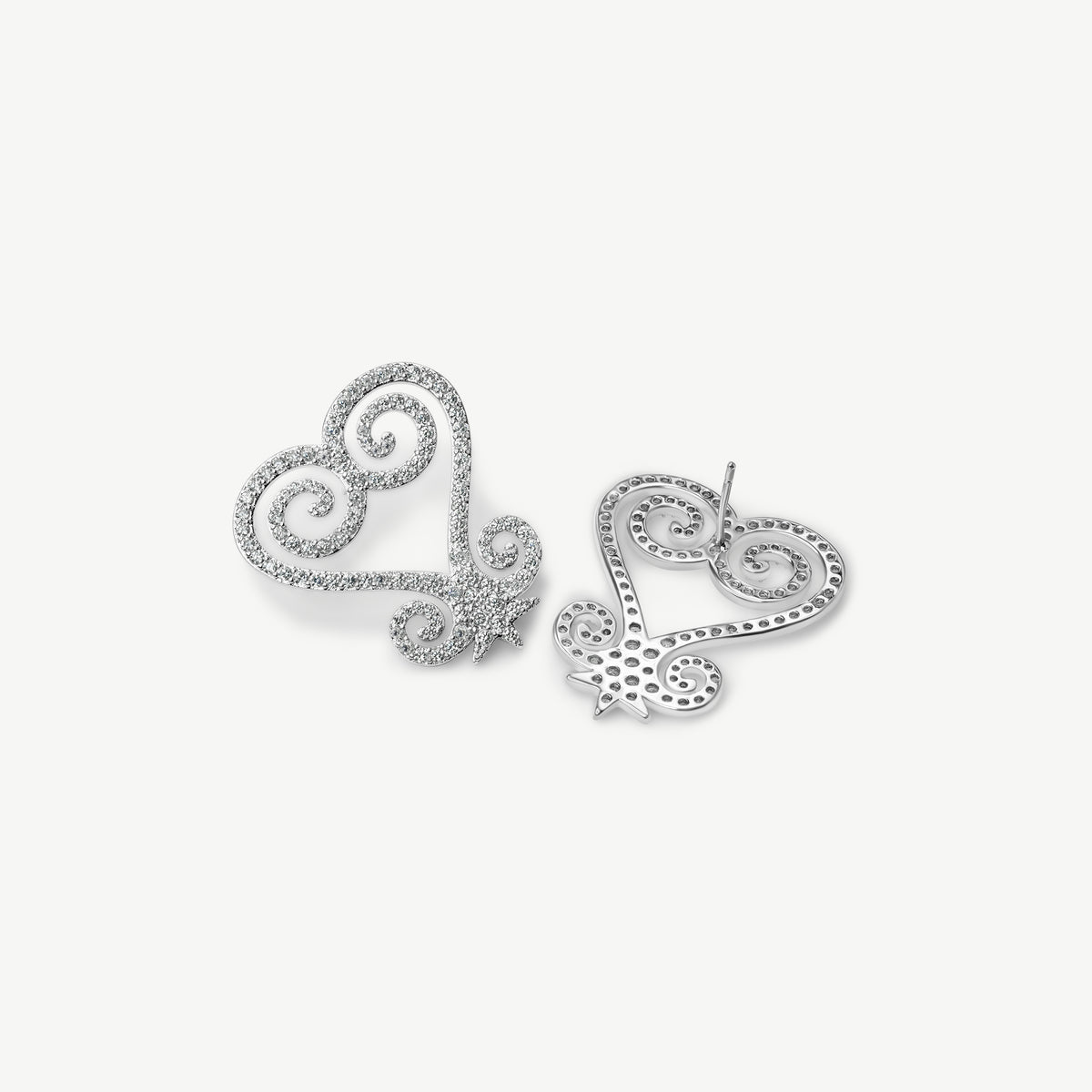 A product shot of CASA London's silver Sankofa Pavé earrings displayed on a clean white background. One earring is shown from the front and the other from the back, highlighting the intricate heart-shaped Sankofa Adinkra symbol meticulously encrusted with shimmering pavé-set stones. This display showcases the brand's unwavering commitment to superior craftsmanship and modern luxury design.