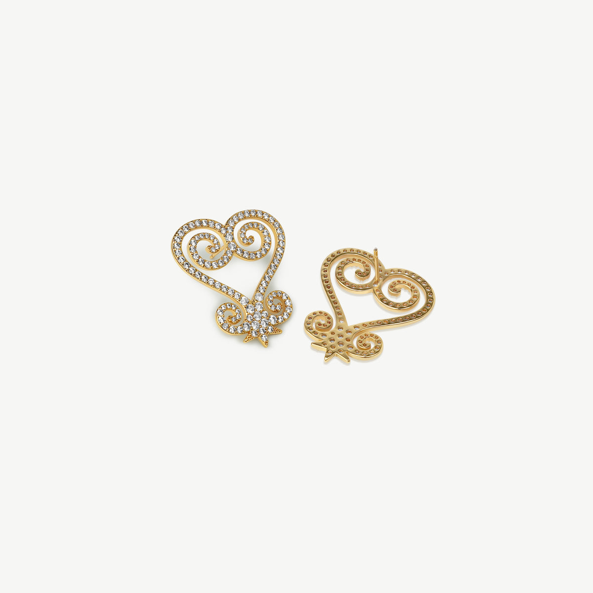 A product shot of CASA London's silver Sankofa Pavé earrings displayed on a clean white background. One earring is shown from the front and the other from the back, highlighting the intricate heart-shaped Sankofa Adinkra symbol meticulously encrusted with shimmering pavé-set stones. This display showcases the brand's unwavering commitment to superior craftsmanship and modern luxury design.